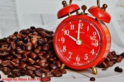 Entkoffeinierter Kaffee schmeckt auch abends: Kaffeebohnen neben eine roten Wecker Entkoffeinierter-Kaffee-schmeckt-auch-abends-gut